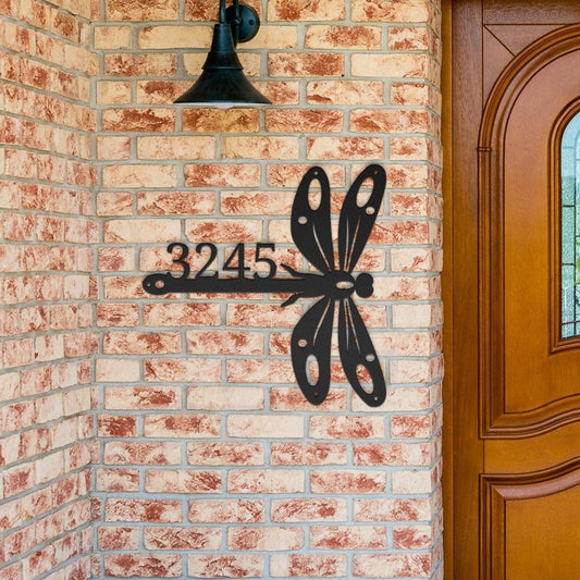 Personalized dragonfly metal address sign mounted on brick wall by wooden door